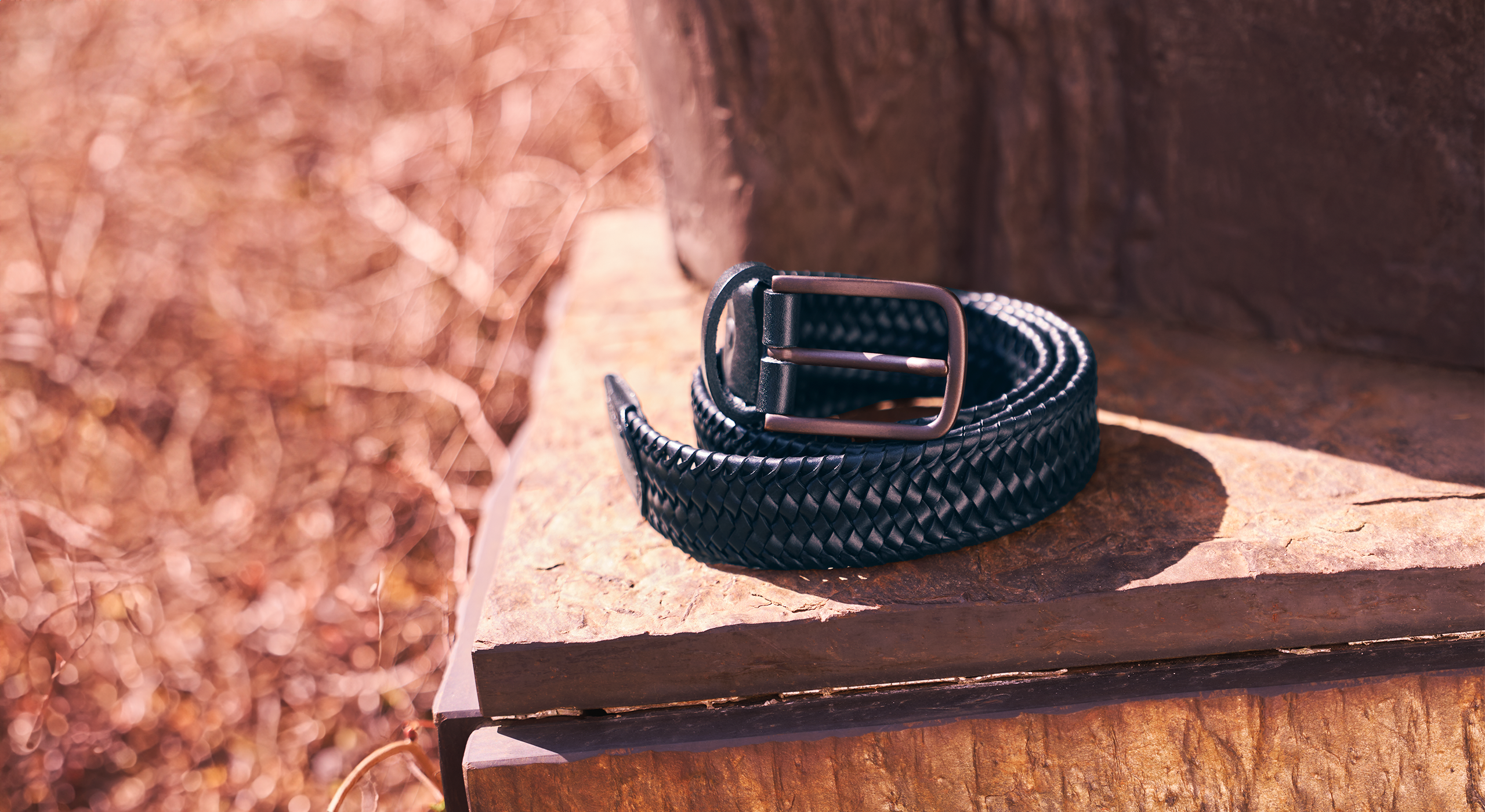 Navy braided belt on a stone surface with a blurred natural background